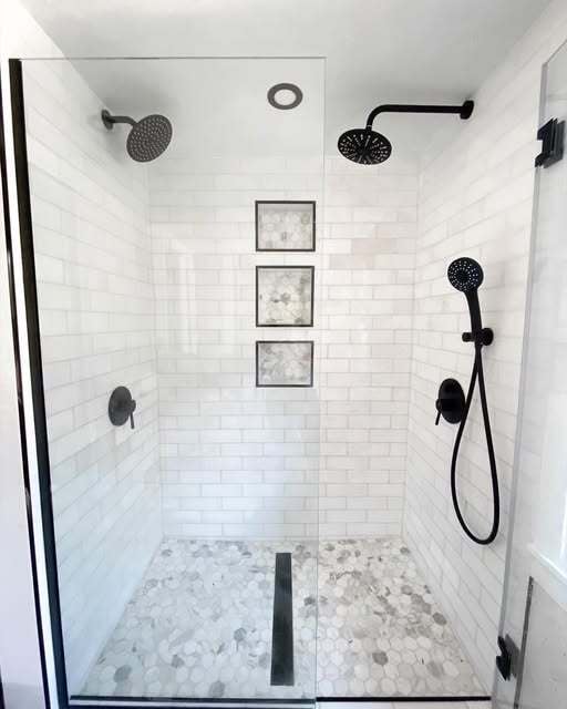 Modern bathroom renovation by ECDreamSpaces showcasing custom tile work and matte black hardware. This walk-in shower remodel features a frameless glass enclosure, marble hexagon tile flooring with a linear drain, and professional subway tile installation.